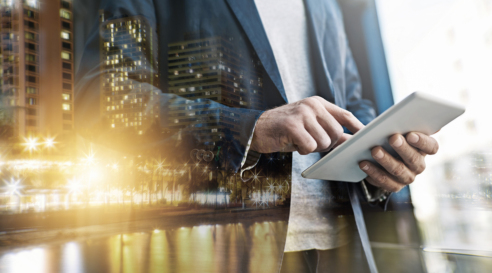 Multiple exposure shot of an unrecognisable businessman using a digital tablet superimposed over a cityscape.